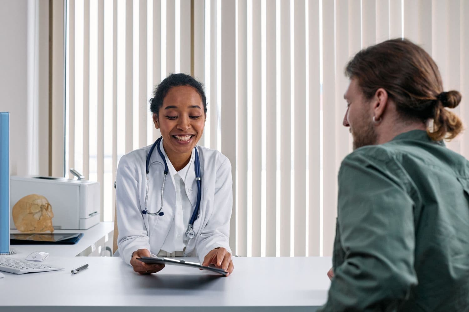 Médica revisa o prontuário em um tablet durante a consulta com o paciente